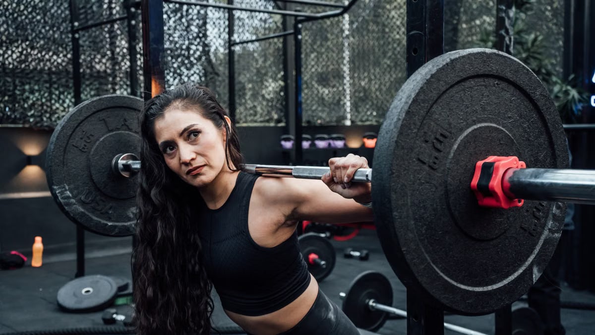 A determined woman lifting weights in a modern gym, embodying fitness and strength.
